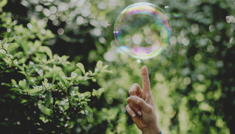 Ett finger som pekar på en bubbla bland grönska
